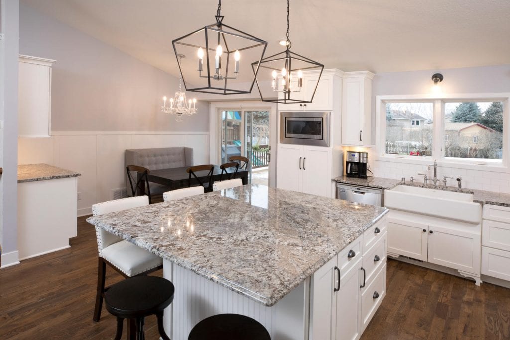 a kitchen remodel in eagan, showcasing an island with gray countertops and white cabinets. above hangs two open-sided hexagonal chandeliers. 