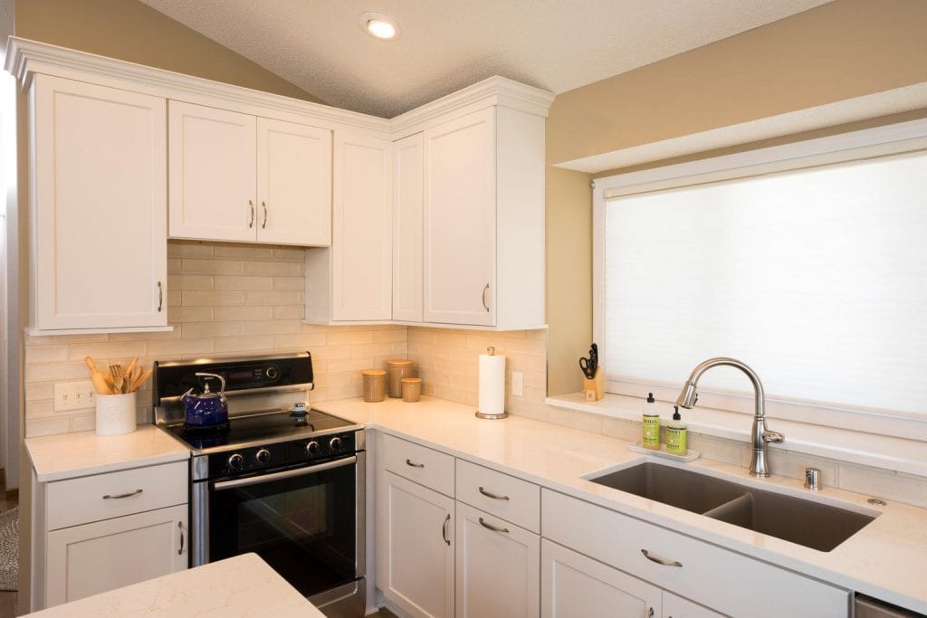 a kitchen with white cabinets, a deep sink and a gorgeous window